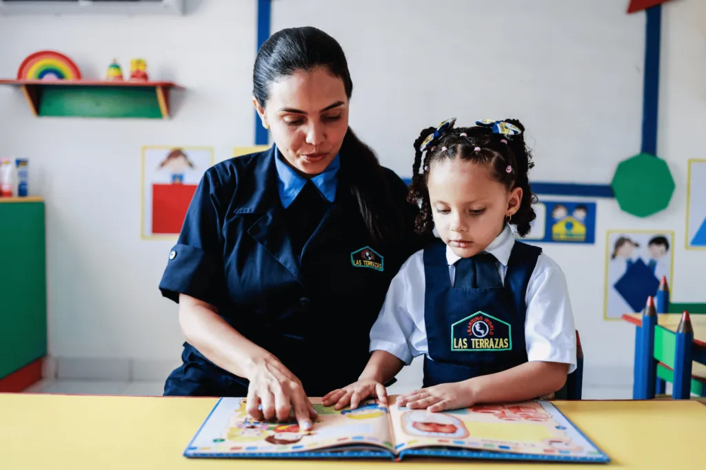 Niña leyendo con su maestra