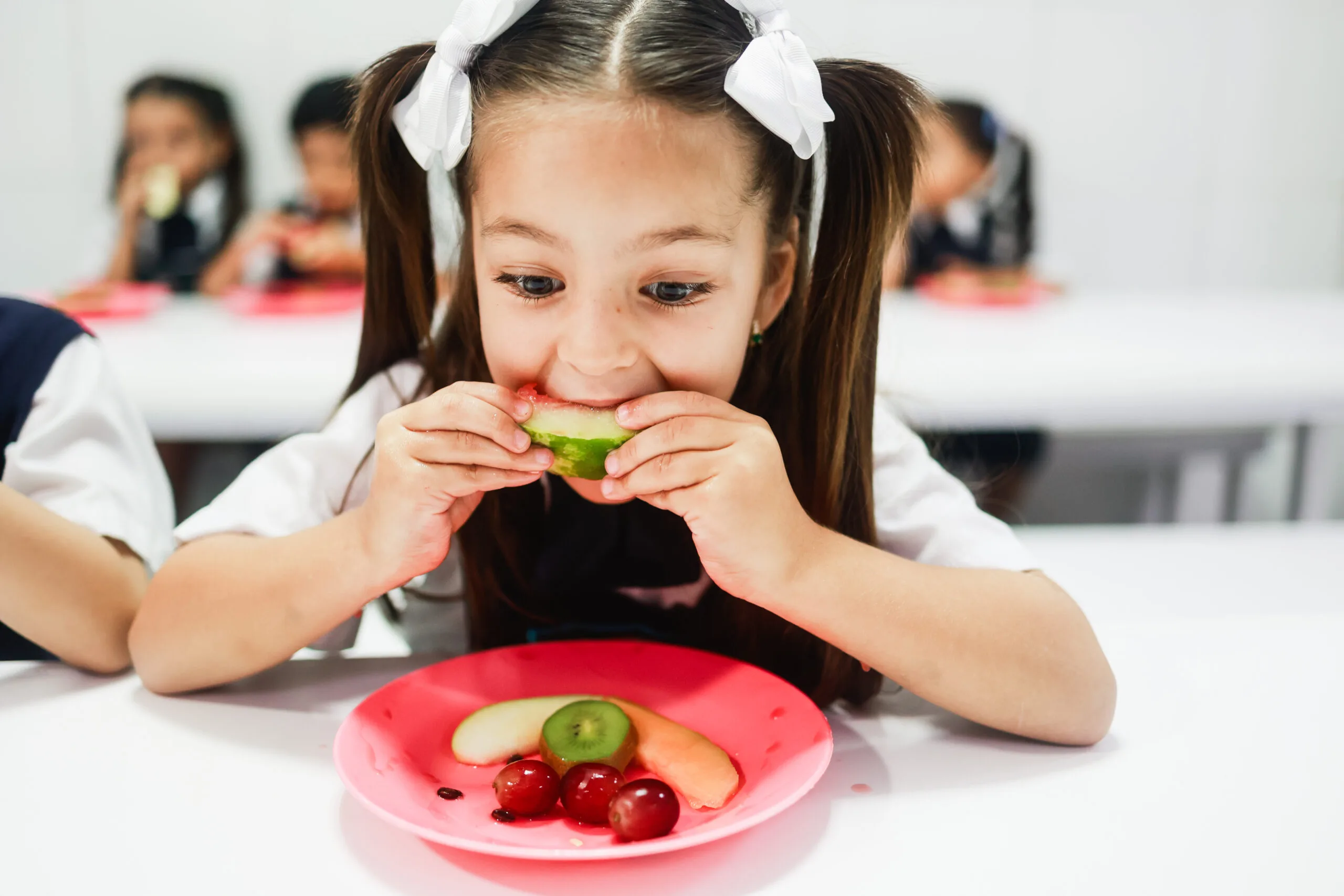 Niña disfrutando de una merienda saludable con frutas frescas en el Preescolar las Terrazas