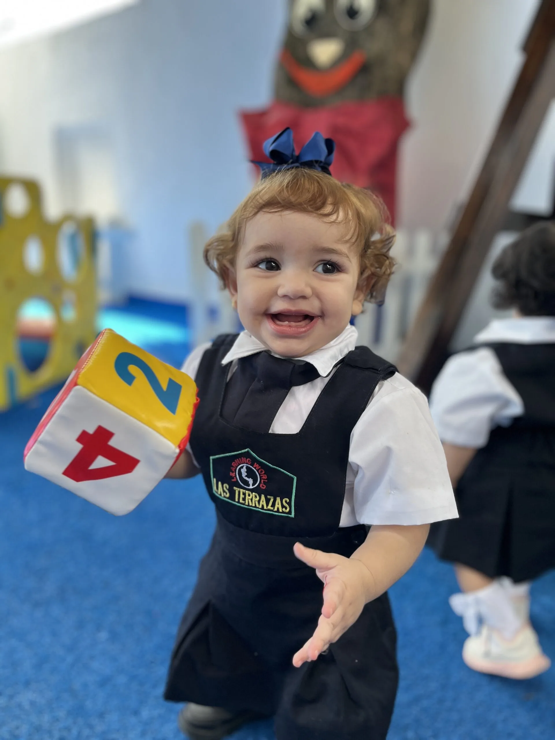 Niña feliz con uniforme del Preescolar Las Terrazas jugando con un cubo didáctico en el salón de clases