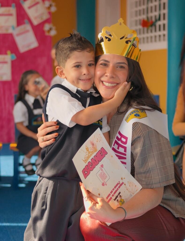 Madre con corona y niño con uniforme escolar en evento del Preescolar Las Terrazas